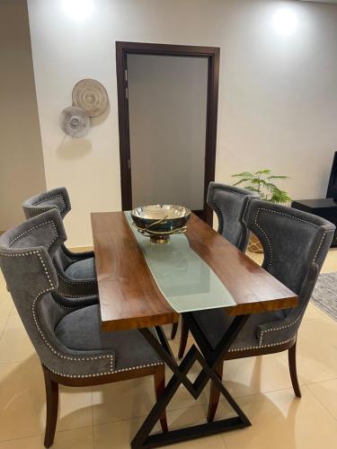 a dining room table with black chairs and a bowl on it at 1 Bedroom Furnished Apartment at Eighteen Islamabad in Islamabad