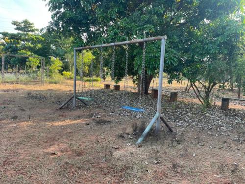 a swing set in a park with a tree at Paradise Quest Nature Farmhouse in Kālapettai