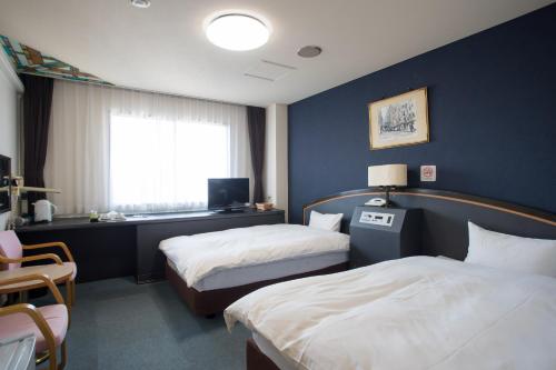 a hotel room with two beds and a window at Hotel Sainthill Nagasaki in Nagasaki