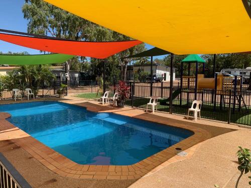 a swimming pool with a large umbrella over it at Karumba Point Holiday & Tourist Park in Karumba