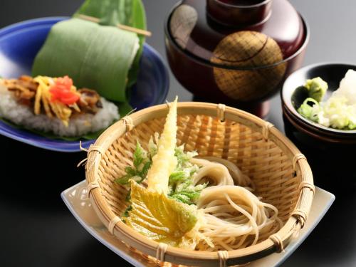 a basket of noodles on a table with plates of food at 志賀高原 白い温泉 渓谷の湯 in Yamanouchi