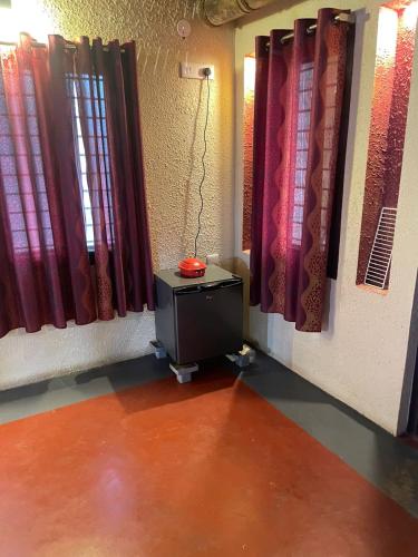 a room with red curtains and a television on a floor at Paradise Quest Nature Farmhouse in Kālapettai