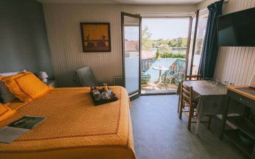 a bedroom with a bed and a table and a balcony at Hôtel Studios Les Acacias in Saint-Paul-lès-Dax