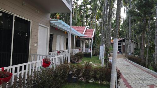 a house with a white fence and some trees at Areca ranches home stay in Chikmagalūr
