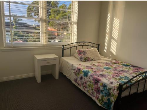 um quarto com uma cama com uma almofada e uma janela em Immaculate rooms in the Heart of the East em Sidney