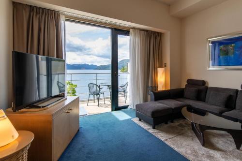 ein Wohnzimmer mit einem Flachbild-TV und einem Sofa in der Unterkunft Hakone Hotel in Hakone