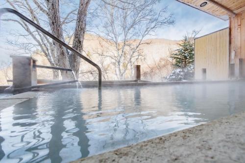 a pool of water with a hose at 志賀高原 白い温泉 渓谷の湯 in Yamanouchi