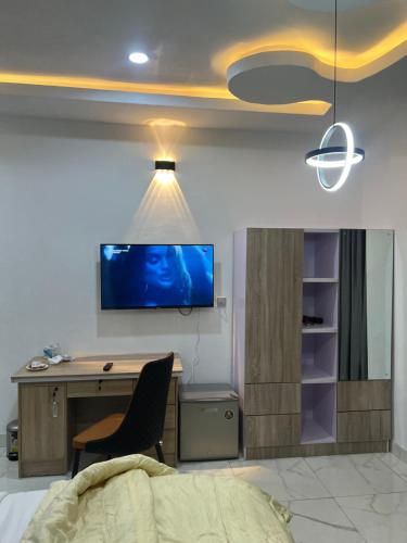 a bedroom with a desk and a tv on the wall at HighX Hotels in Port Harcourt