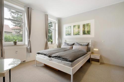 a white bedroom with a bed and two windows at Fewo zum alten Bahnhof 