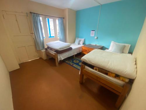 Cette petite chambre comprend 2 lits et une fenêtre. dans l'établissement Himalayan lodge and Restuarant, à Namche