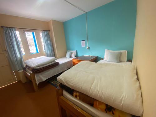 Namche的住宿－Himalayan lodge and Restuarant，小房间设有两张床和窗户