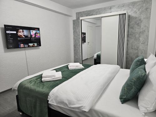 a bedroom with a large bed with a tv on the wall at Mona Central Apartment in Hunedoara
