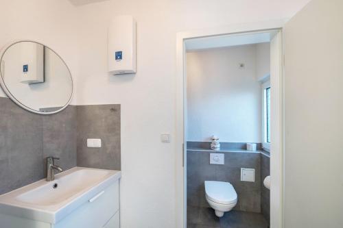 a bathroom with a sink and a toilet and a mirror at Strandnaher Bungalow in Dierhagen