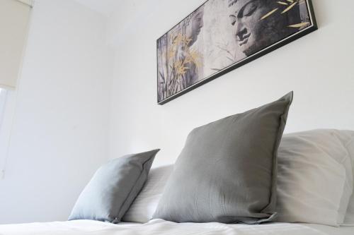 uma cama com duas almofadas e uma fotografia na parede em Mercury Apartment em Livadhia