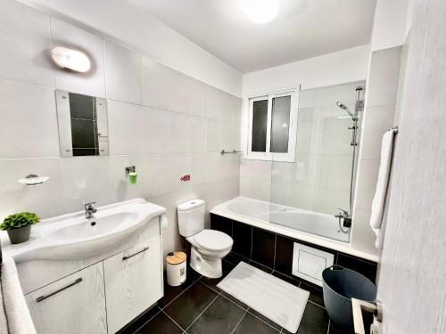 uma casa de banho branca com um lavatório e um WC em Mercury Apartment em Livadhia