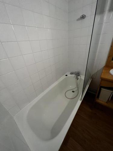 La salle de bains est pourvue d'une baignoire blanche avec un robinet. dans l'établissement appartement dans station Super Besse 4ou5 pers piscine, à Besse-et-Saint-Anastaise