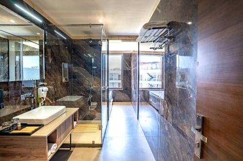 兰纳加Shervani Pebbles & Pines Resort & Spa, Corbett的带水槽和玻璃淋浴间的浴室