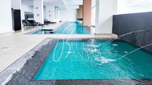 a pool with a water fountain in a building at The Apple Suites Melaka by BlueBanana in Melaka