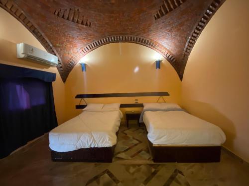 two beds in a room with an arched ceiling at Oasis inn House in Mandīshah