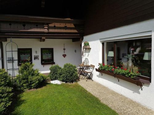 ein Haus mit einer Terrasse mit einem Tisch und Blumen in der Unterkunft Appartement Lärchenhof 3 in Ehrwald