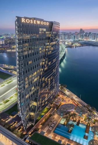 a tall building with a sign on it next to a body of water at Rosewood Abu Dhabi in Abu Dhabi