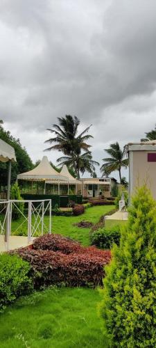 a garden with a pavilion and palm trees in the background at La serene nandihills in Nandi