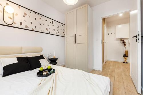 a white bedroom with a bed with a tray of fruit on it at Apartament Suna in Sopot
