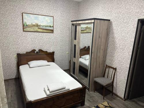 a bedroom with a bed and a mirror and a chair at REAL TASHKENT Inn in Tashkent