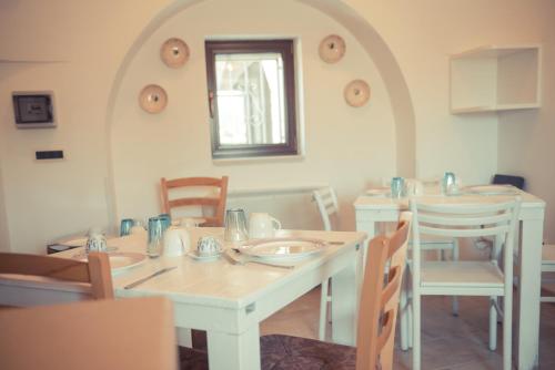 una sala da pranzo con tavolo e sedie bianchi di I Trulli Di Badi a Locorotondo