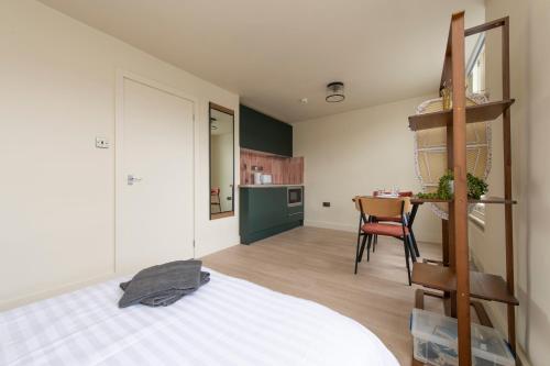 a bedroom with a bed and a kitchen with a table at The CoDalston in London