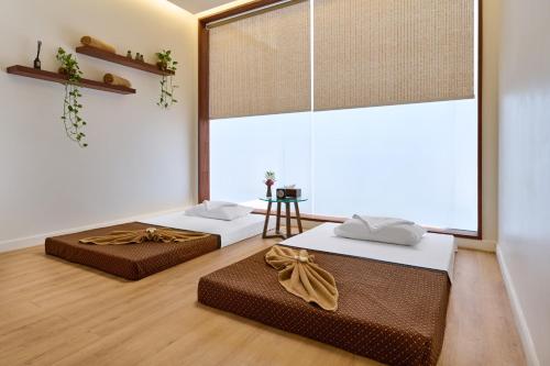 two beds in a room with a large window at Plantation Urban Resort & Spa in Phnom Penh