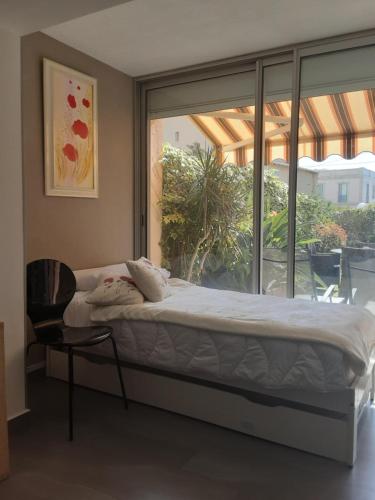 Ce lit se trouve dans un dortoir doté d'une fenêtre et d'une chaise. dans l'établissement Studio rdj 24 m2 et piscine, à Vallauris