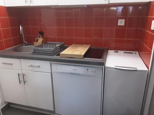 - une cuisine avec des placards blancs, un évier et du carrelage rouge dans l'établissement Studio rdj 24 m2 et piscine, à Vallauris
