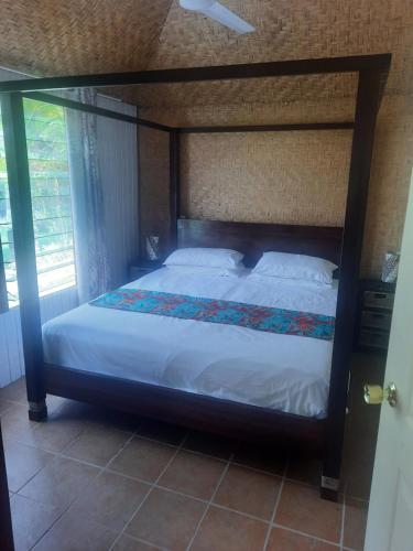 ein Bett in einem Schlafzimmer mit einem großen Himmelbett in der Unterkunft Orchid Island one bedroom Bure in Pacific Harbour