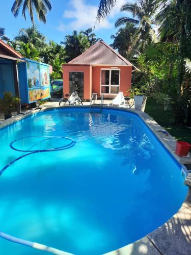 a large blue swimming pool in front of a house at Orchid Island one bedroom Bure in Pacific Harbour