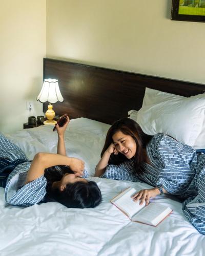 two women laying on a bed with a book at Hokke Lumbini in Lumbini