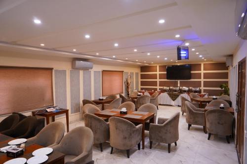 ein Restaurant mit Tischen und Stühlen und einem Flachbild-TV in der Unterkunft Hotel Avalon Suites in Multan