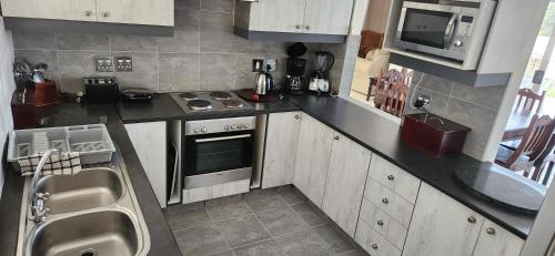 a small kitchen with a stove and a microwave at Picollo Bocca Villa Kleinmond in Kleinmond