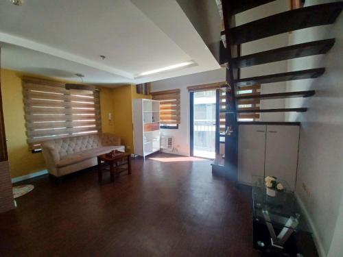 ein Wohnzimmer mit einem Sofa und einigen Fenstern in der Unterkunft ADB Tower - Loft Unit Hotel Vibe in Manila