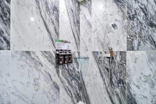 a bathroom with white marble walls and a shower at February Hotel Gimhae in Gimhae