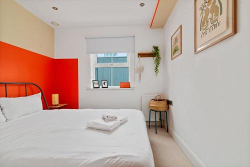 een slaapkamer met een wit bed en een oranje muur bij GuestReady - Artsy Penthouse in Heart of the City in Londen