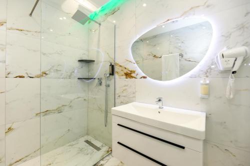 uma casa de banho com um lavatório e um chuveiro com um espelho. em Tesi Apartment em Vlorë