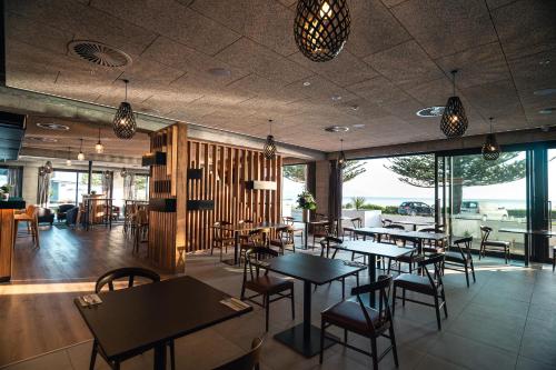 a restaurant with tables and chairs and windows at Sudima Kaikōura in Kaikoura