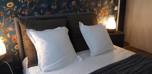 - un lit avec des oreillers blancs et un mur fleuri dans l'établissement Le Petit Honfleur, à Honfleur