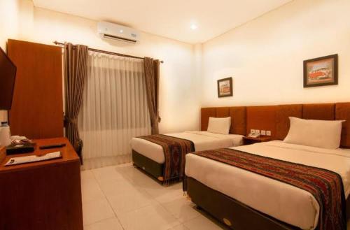 a hotel room with two beds and a desk at Diva Lombok Resort in Senggigi 