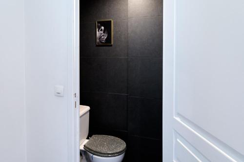 La salle de bains est pourvue de toilettes et d'un mur noir. dans l'établissement Les Suisses Apartment Zentral in der schönen Altstadt von Le Suquet 5 min zum Strand WLAN, à Cannes