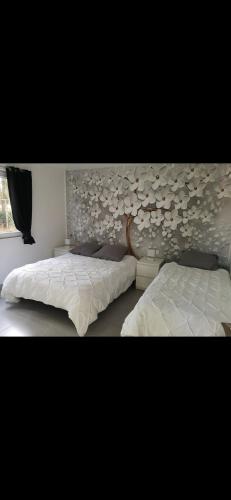 - une chambre avec 2 lits et un mur orné de fleurs dans l'établissement Villa Chrispas, à Cavalaire-sur-Mer
