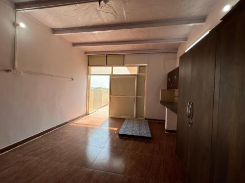 an empty room with a kitchen with a door and a rug at Vinayak Homestay in Mathura