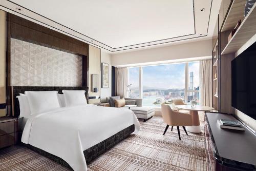 a bedroom with a large bed and a living room at Four Seasons Hotel Hong Kong in Hong Kong