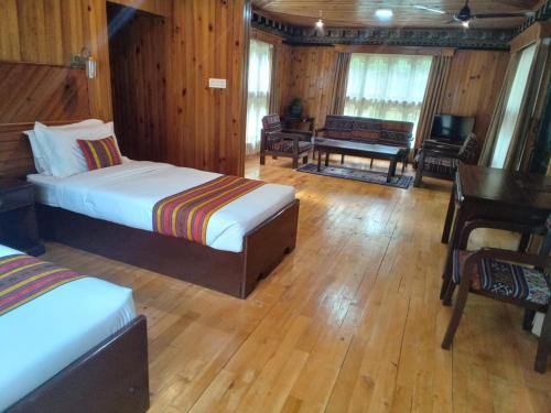 a bedroom with two beds and a table and a desk at Hotel Olathang in Paro